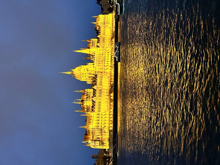 Hungarian Parliament Building glowing golden at night across shimmering Danube waters.