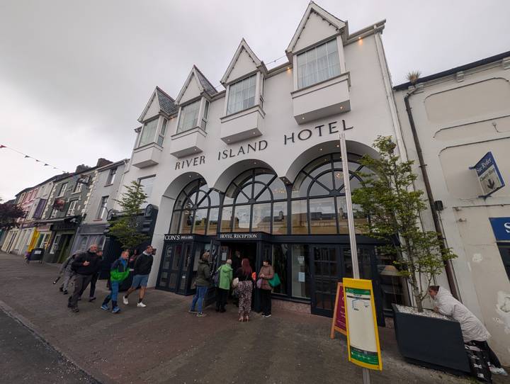 Tour group gathers outside the white-fronted River Island Hotel on a small Irish town street.