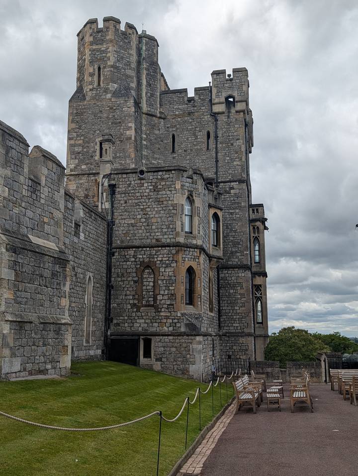 Stone towers and windows of Windsor Castle rise against a grey sky.