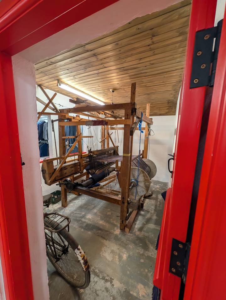 Wooden hand-loom with threads set up inside a small weaving workshop.