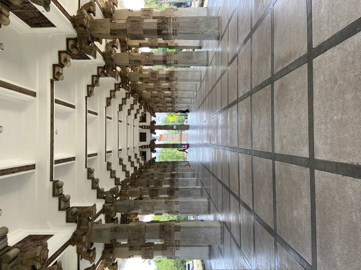 Symmetrical stone colonnade of a memorial hall with geometric ceiling and tiled floor