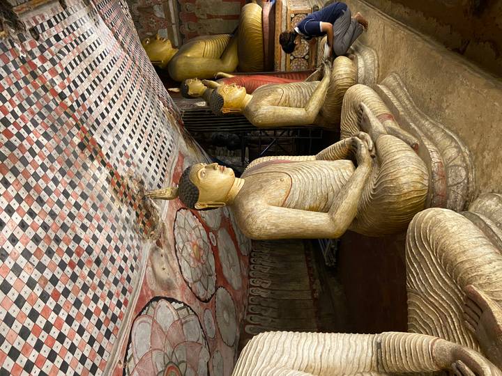 Seated Buddha statues inside a richly painted rock-cut cave temple