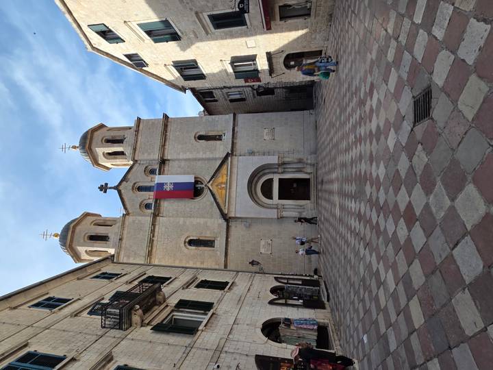 Stone-faced Serbian Orthodox church fronting a tiled square within medieval walls