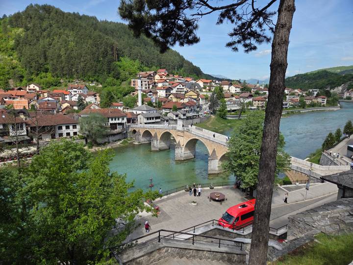 Historic multi-arch stone bridge over turquoise river seen from elevated viewpoint