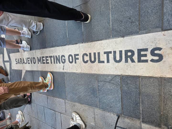 Pavement inscription marking 'Sarajevo Meeting of Cultures' with tourists’ feet around