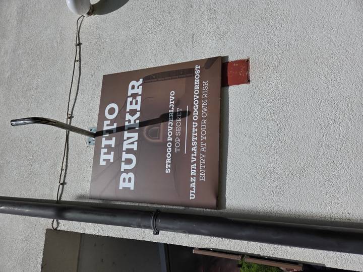 Brown sign on wall reading 'Tito Bunker' with multilingual warnings