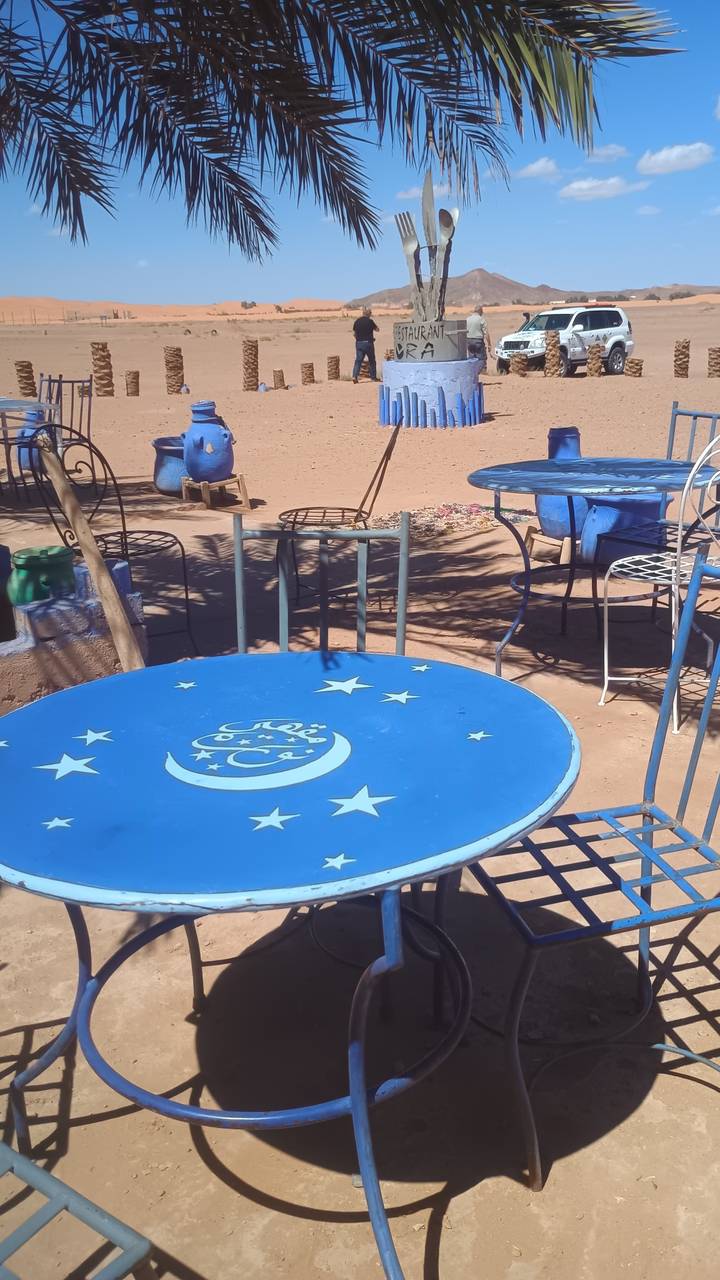 Blue metal tables and chairs decorated with stars and moons at an outdoor desert café.