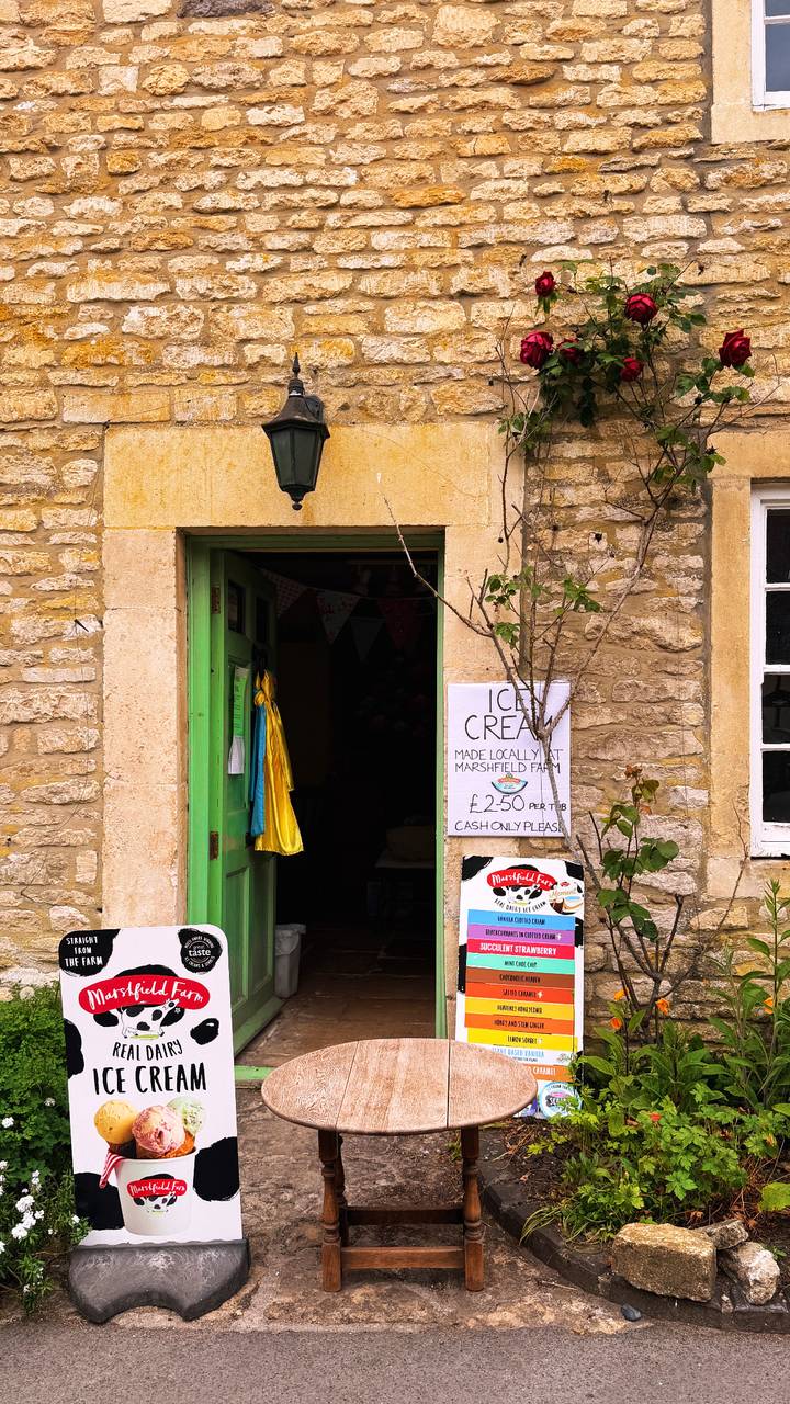 A stone storefront with bright green door advertises locally made ice cream with handwritten signs.