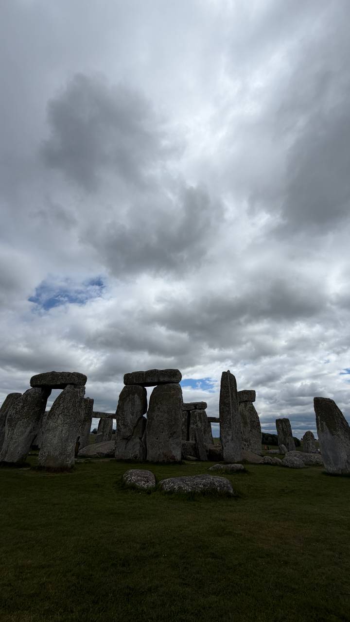 Massive prehistoric stones of Stonehenge stand silhouetted against a dramatic cloudy sky.