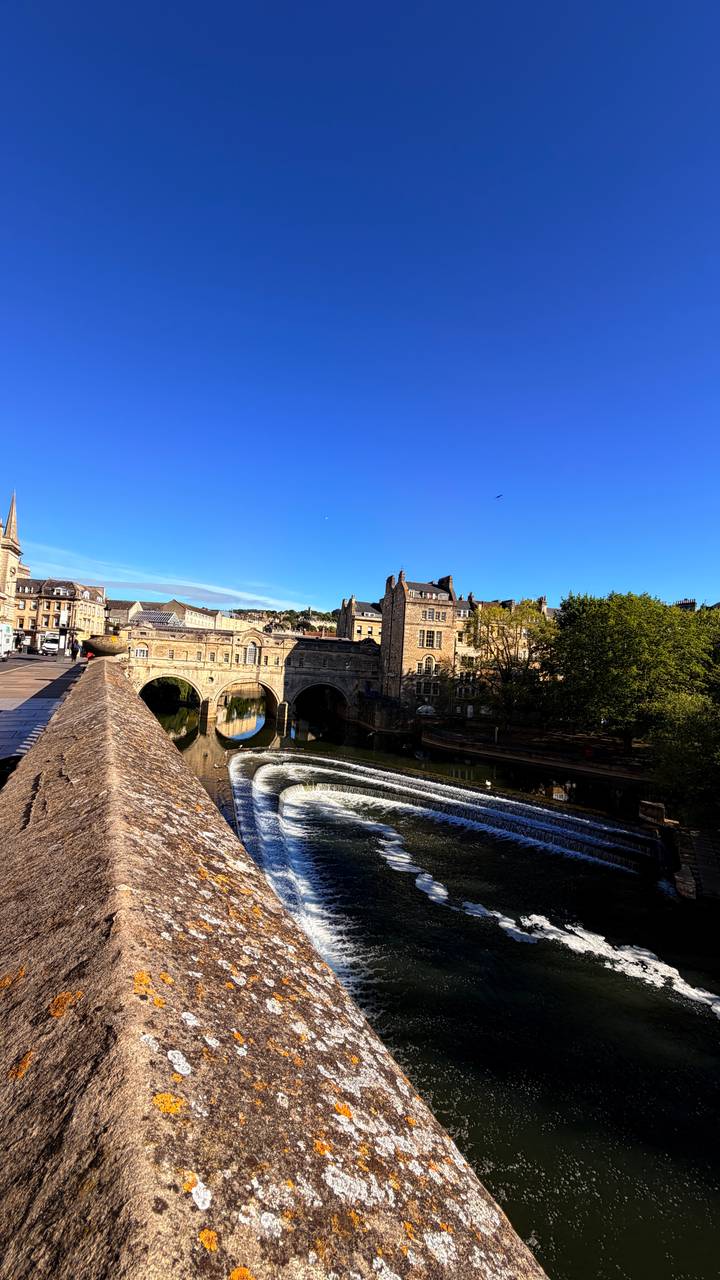 Bath’s Pulteney Bridge and weir curve gracefully over the River Avon on a sunny morning.