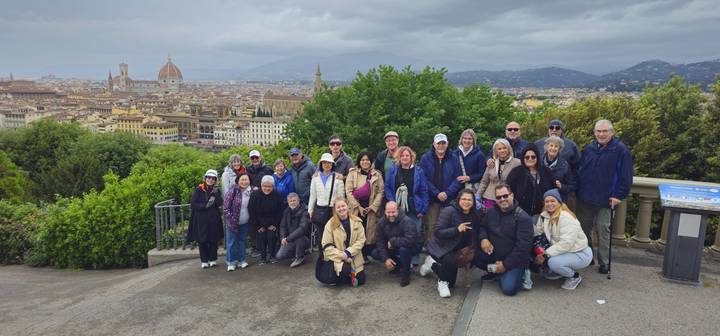 Large tour group poses on a viewpoint above Florence with the Duomo and cityscape spread below.