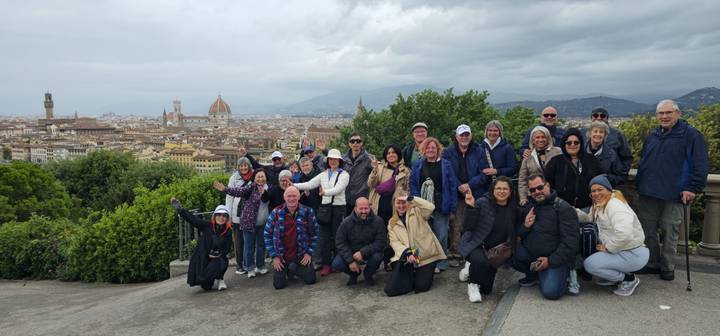 Tour participants cheer and gesture while overlooking Florence’s terracotta rooftops and famous dome.