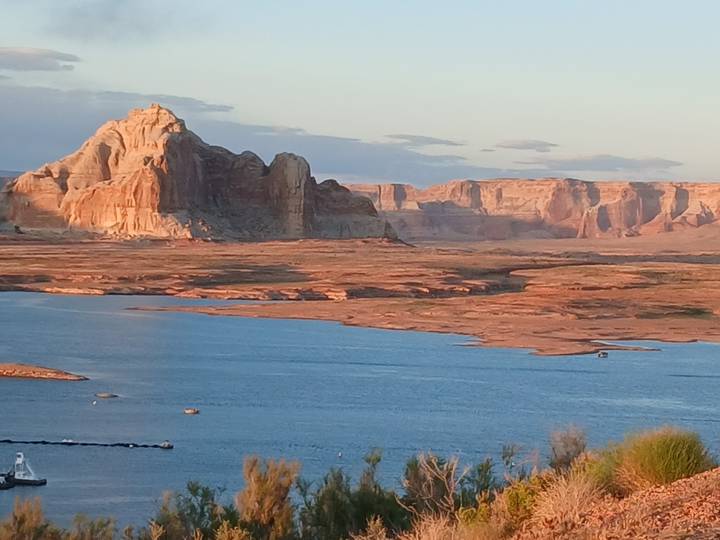 Blue lake waters framed by striking red-rock buttes and mesas in warm late-day light.