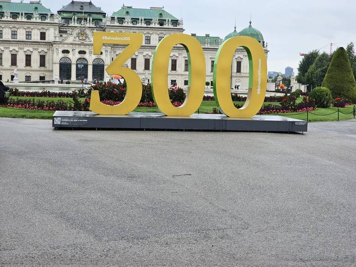 Large yellow three-digit installation "300" in front of a historic palace facade.