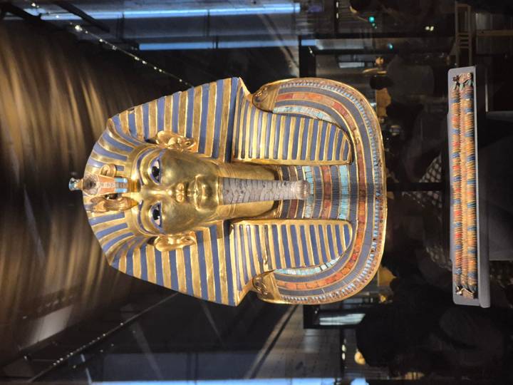 Close-up of Tutankhamun's golden funerary mask displayed under dramatic lighting.