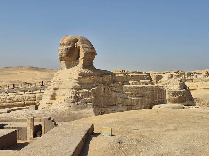 Side profile of the Great Sphinx with its monumental limestone body against a clear sky.