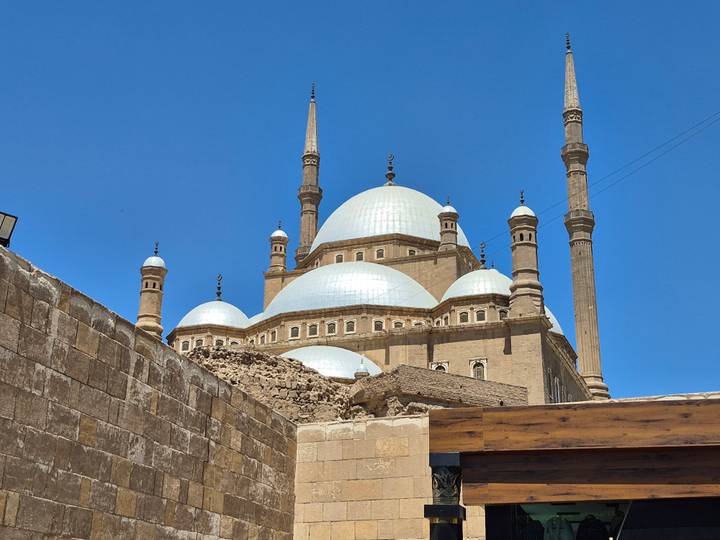 The domes and minarets of the Mosque of Muhammad Ali gleaming under a bright blue sky.