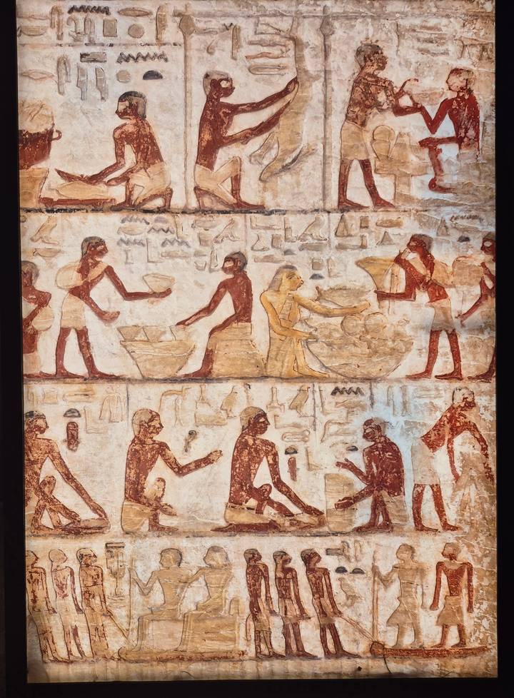 Ancient tomb painting depicting workers mixing and carrying grain, with faded red and ochre tones.
