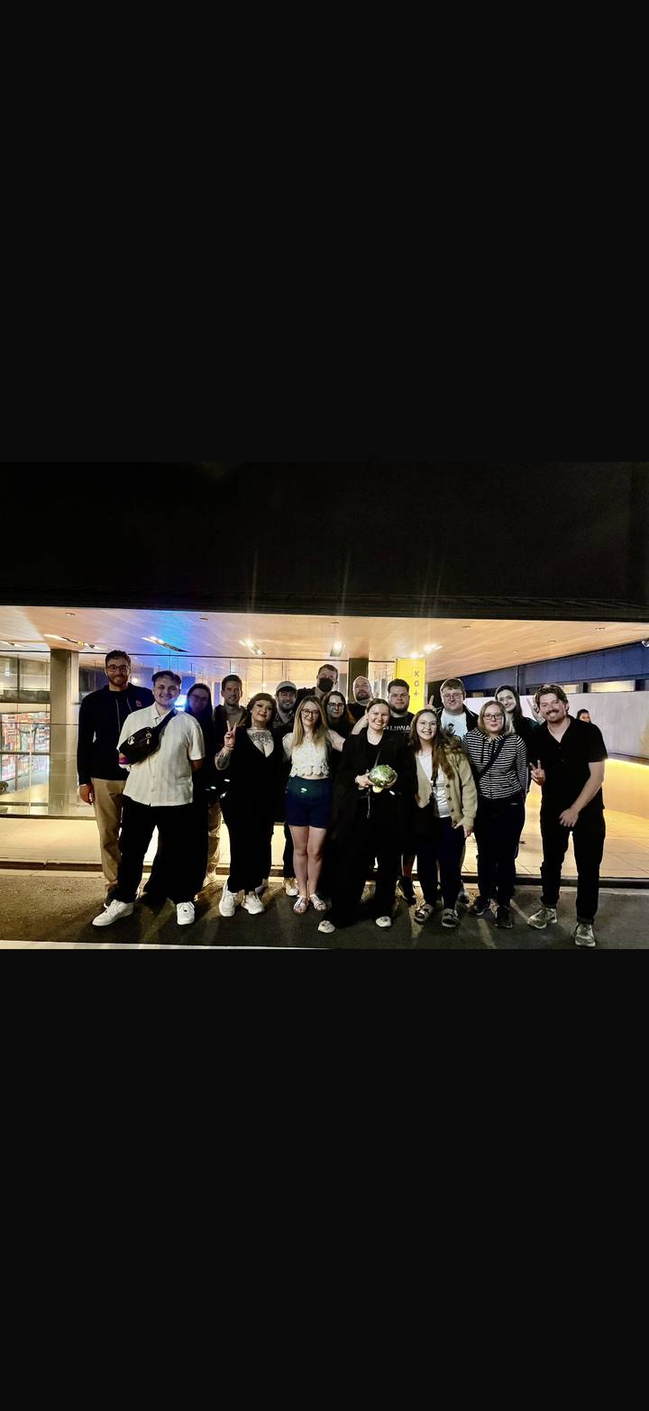 Large group photo taken at night outside a modern lit building after an event.