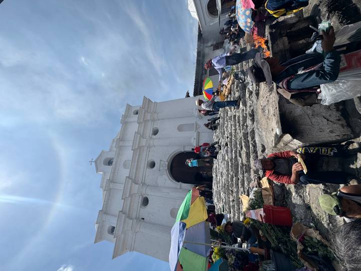 Locals and visitors gather on the stone steps of Chichicastenango’s white church amid incense smoke.