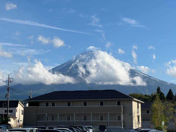 Snow-capped Mount Fuji emerging through clouds above suburban rooftops