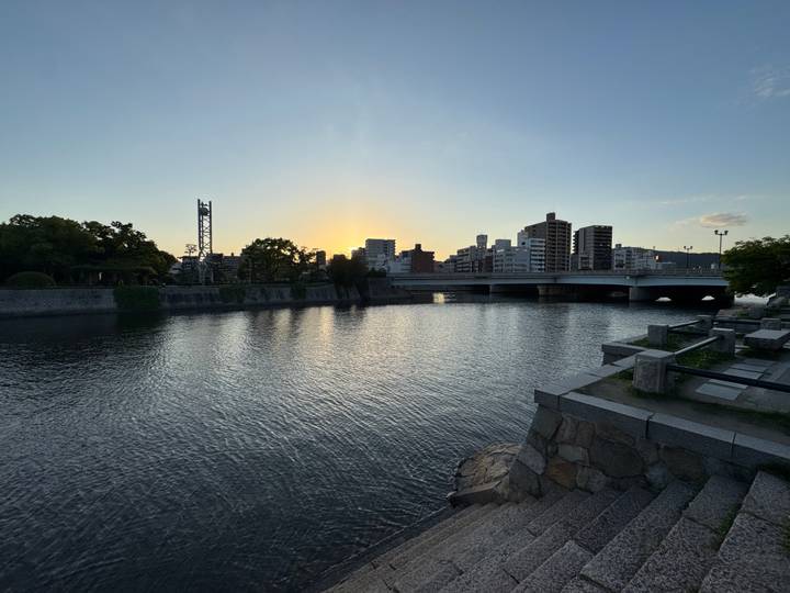 River in Hiroshima at dusk with bridge and city skyline against setting sun