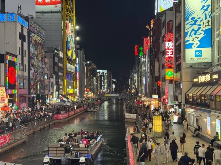 Lively Dotonbori canal at night with neon signs and crowds in Osaka