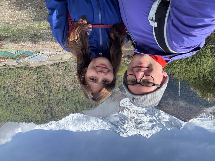Selfie of couple in trekking gear with snowy mountains behind