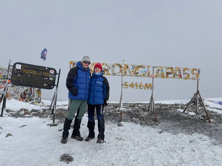 Hikers posing at snowy 5416m Thorong La Pass sign