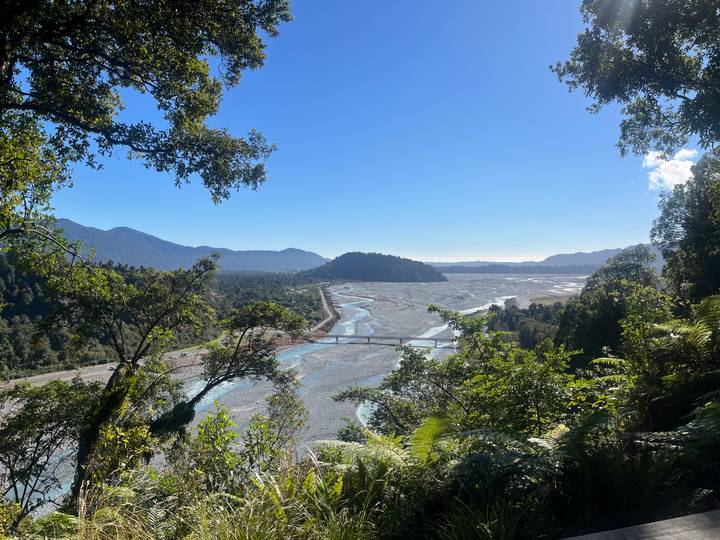Wide view over braided river valley with long bridge stretching toward distant coast