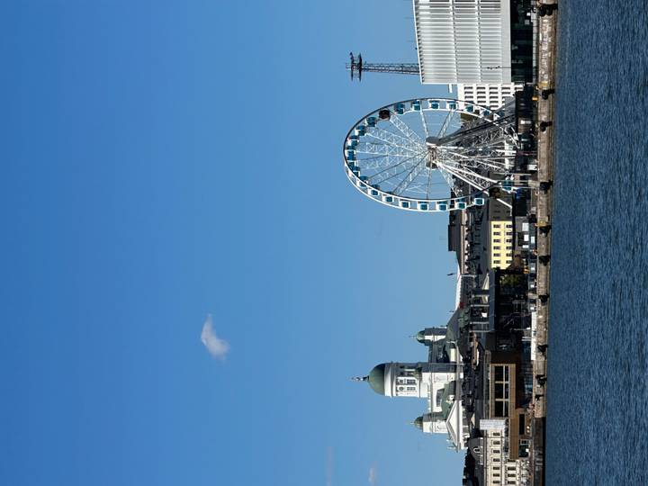 Skyline of Helsinki featuring the white cathedral dome and a large waterfront Ferris wheel
