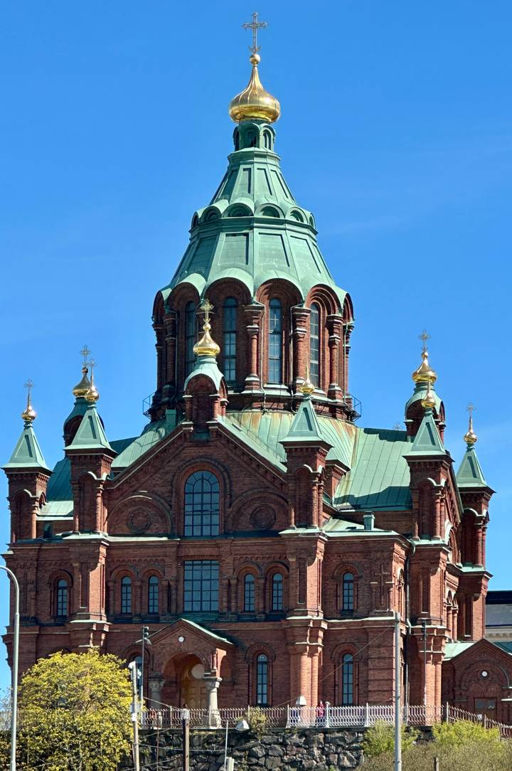 Close-up of red-brick Uspenski Cathedral crowned with green copper domes and golden crosses