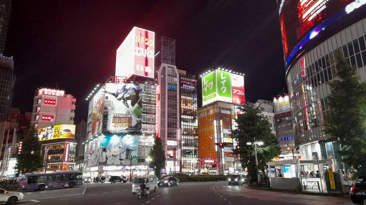 Vibrant night scene of Shibuya with neon billboards, busy traffic and illuminated buildings.