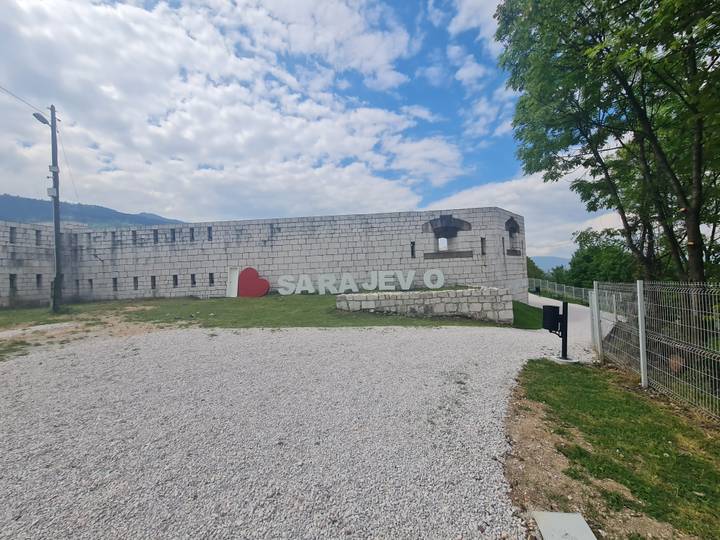 "I ♥ Sarajevo" sign mounted on a cement wall at a historic fort on a bright cloudy day.