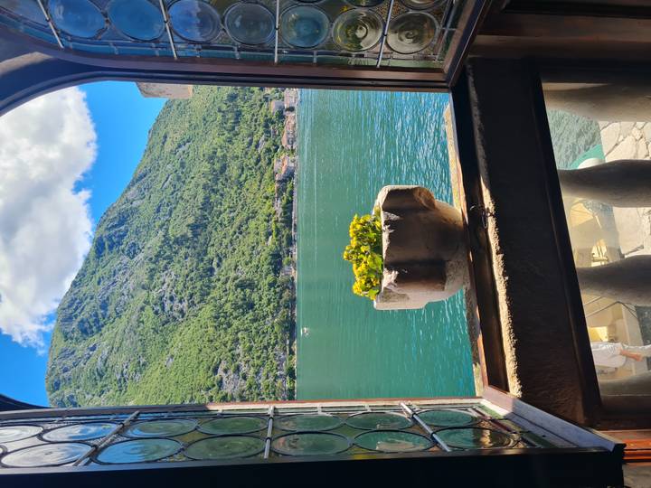 Peaceful window view over deep-blue bay and green hills, with a stone flowerpot in the foreground.