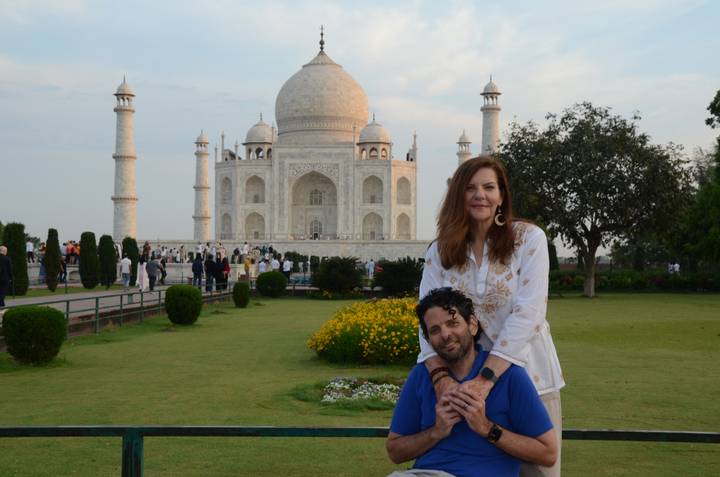 Couple poses affectionately in front of the iconic white marble Taj Mahal and its gardens.