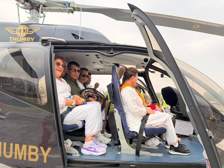 Passengers smile from the open door of a branded helicopter on the tarmac, ready for a pilgrimage flight.