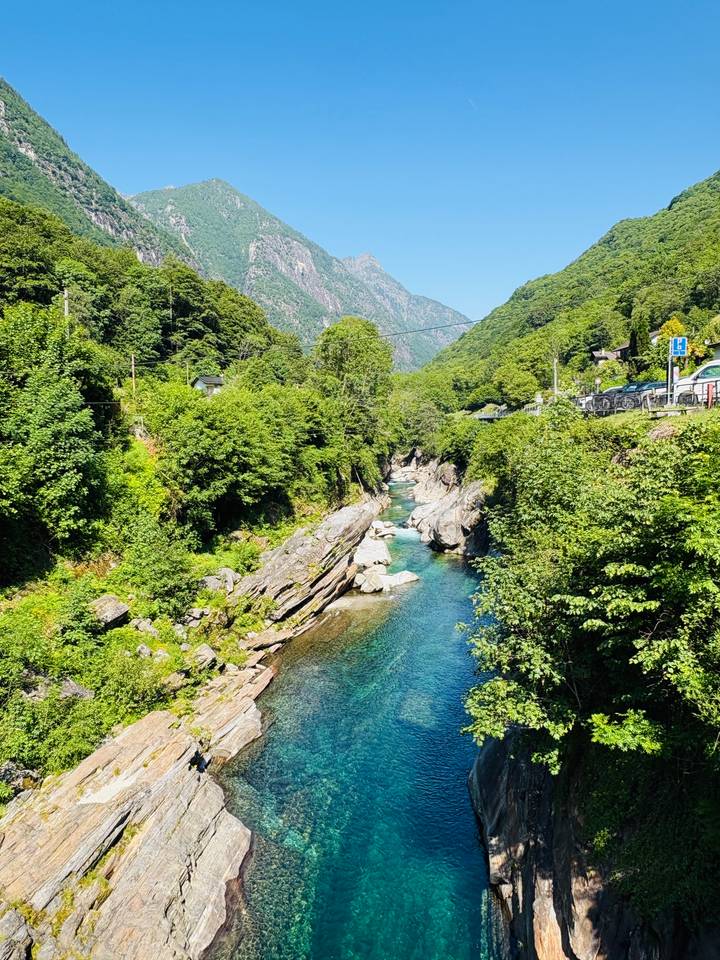 Turquoise mountain stream flowing between lush green forested banks and rocky outcrops