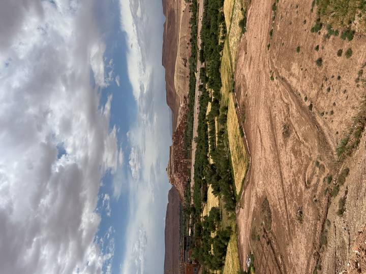 Distant view of the fortified adobe village of Ait Benhaddou set amid semi-arid plains under a moody sky.