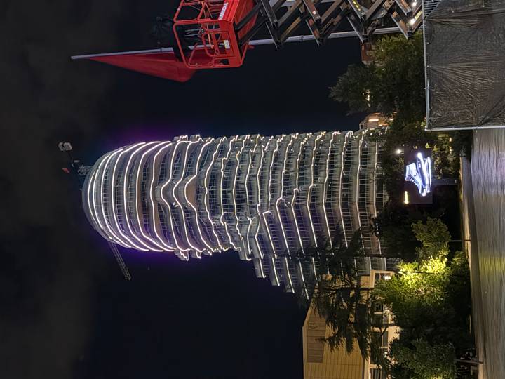 Futuristic high-rise tower in Tirana illuminated with flowing white LED stripes against the night sky.