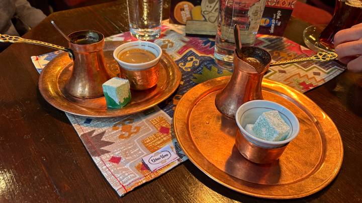 Traditional Bosnian coffee service on copper trays with Turkish delight in a cosy café setting.