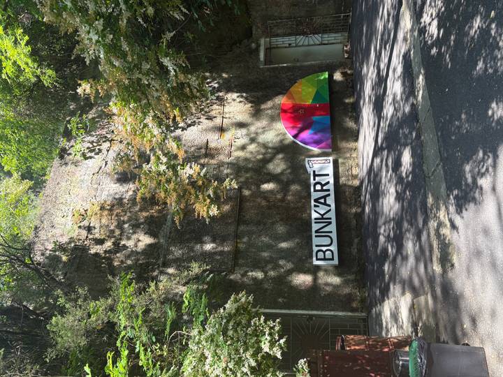 Concrete bunker entrance in a leafy setting with colourful BUNK'ART 1 logo banner.