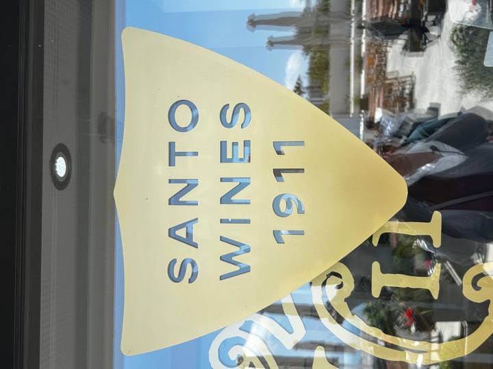 Frosted glass door with large yellow shield logo reading 'Santo Wines 1911' reflecting outdoor terrace.