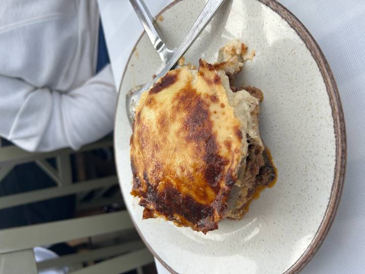 Slice of traditional moussaka on a rustic ceramic plate.