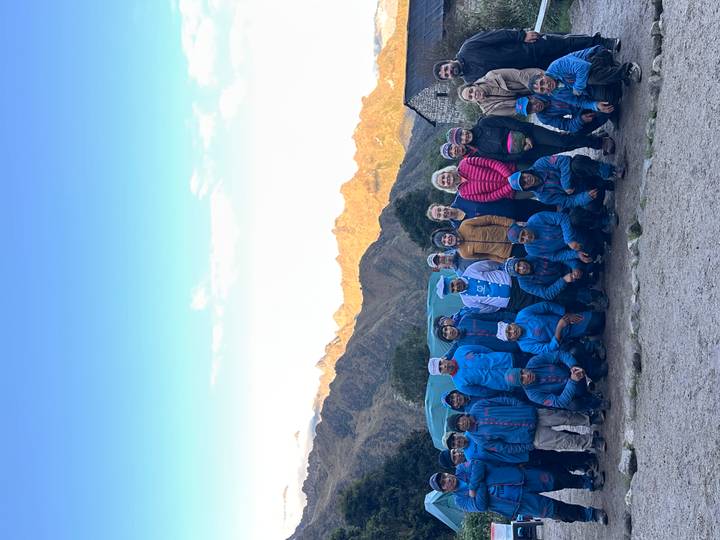 Porters and trekkers pose together in front of misty Andes peaks at dawn on the Inca Trail.