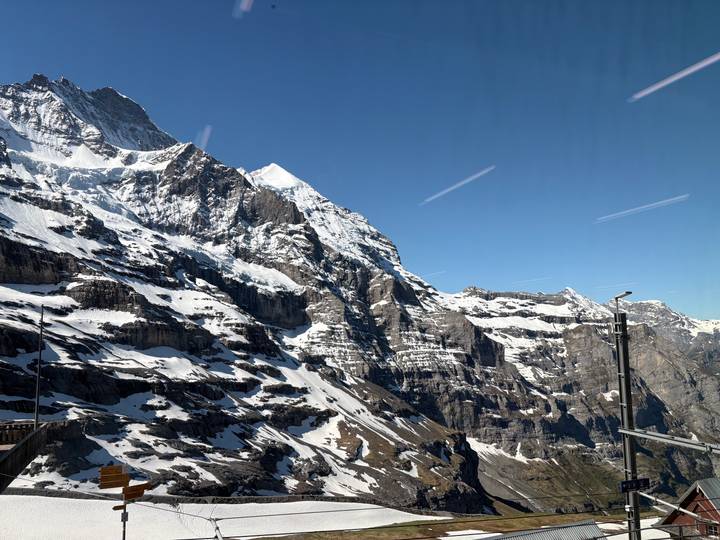 Snow-covered rugged alpine peaks viewed through large panoramic windows.