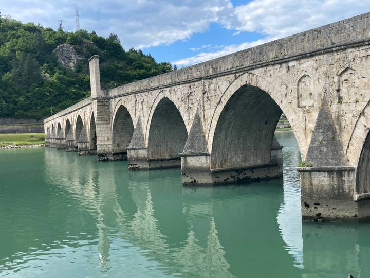 Stone arch bridge with multiple spans crossing turquoise river at Višegrad.