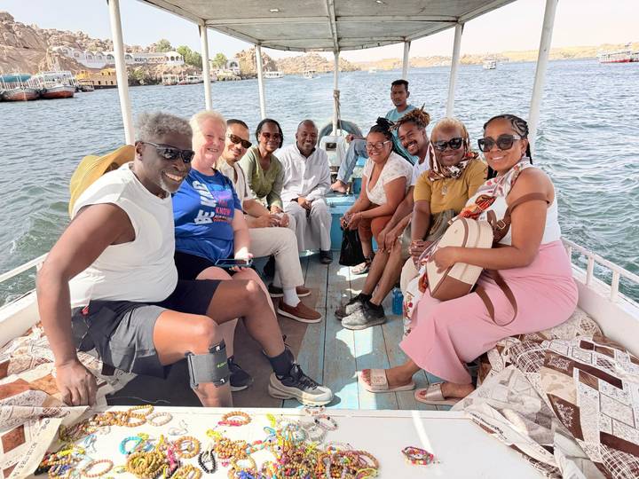 Smiling tour group sits aboard a small boat on the Nile River.