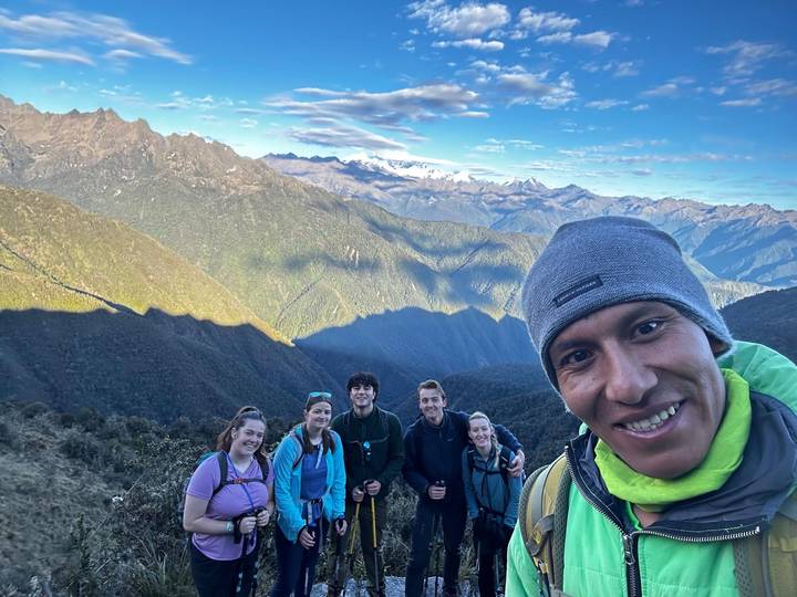 Smiling trekking group on the Inca Trail with dramatic Andean peaks behind.