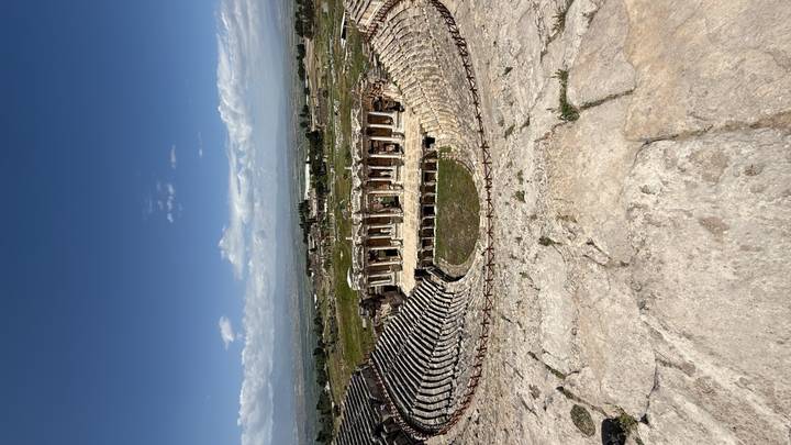 Wide view over the well-preserved stone amphitheatre of Hierapolis on a bright day.